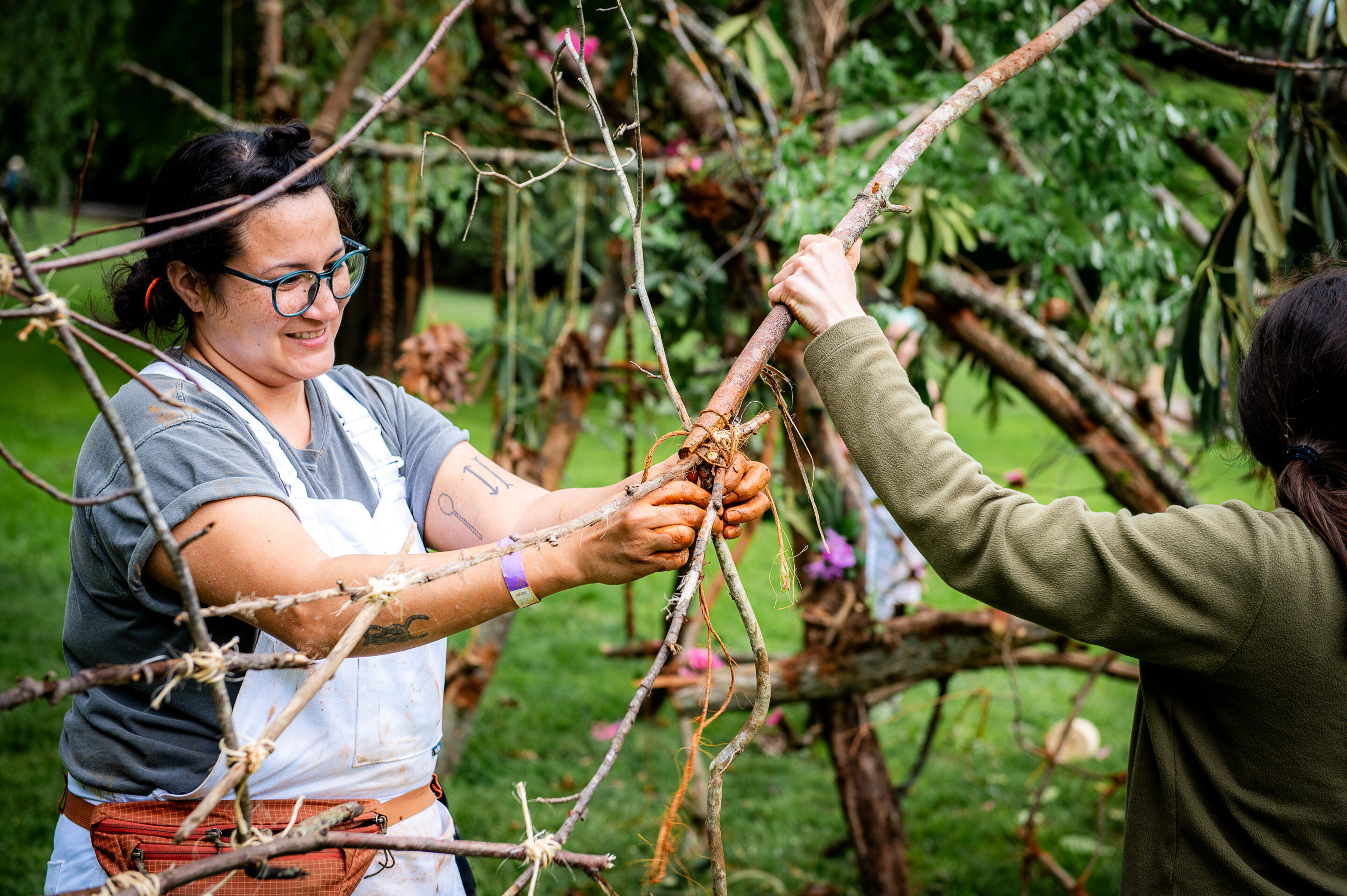 A woman in a white apron crafts with trees and vines