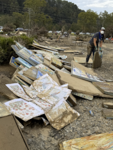 Artist next to pile of Helene damaged paintings in the the RAD
