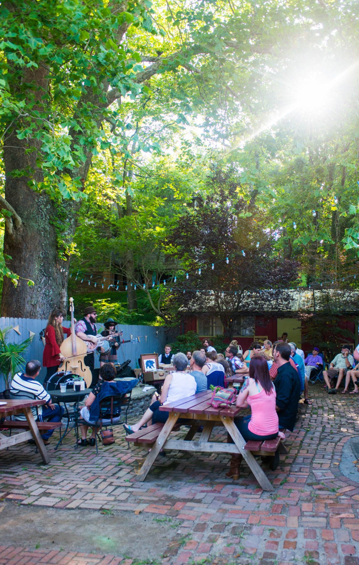 people sit at tables outside listening to music